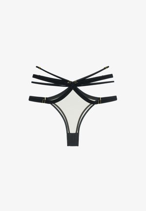 Tanga noir avec plusieurs sangles noires croisées à l'arrière, doté d'accents en métal doré et d'un devant en tissu lisse de couleur claire.