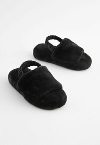Pantofole in morbido tessuto a pelo nero, con punta quadrata, ampia fascia superiore e strap elastico attorno al tallone per una vestibilità sicura.
