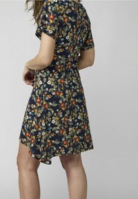 Marinblå klänning med korta ärmar, med ett mönster av flerfärgade blommor och blad. Sömmen är något kortare på ena sidan.
