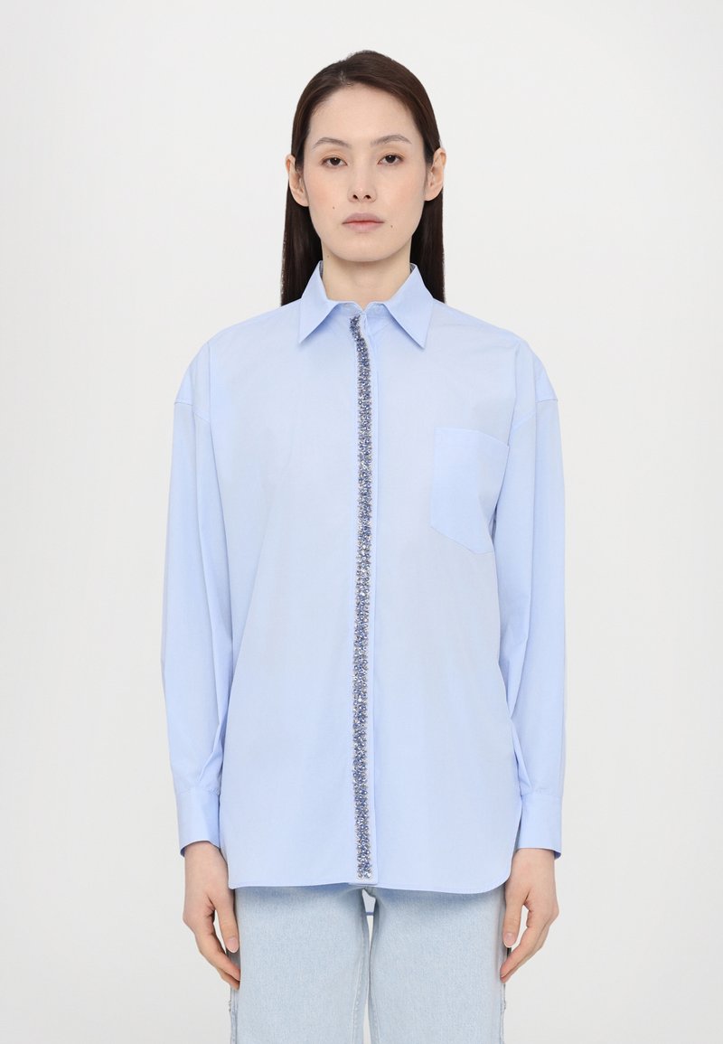 Blue long-sleeve shirt with a decorative front placket, button-down collar, and single chest pocket. Made of a smooth, woven fabric.