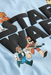 Tricou de culoare albastru deschis cu text de culoare neagră "STAR WARS" și personaje de desene animate, inclusiv un robot și personaje iconice în culori vivace.