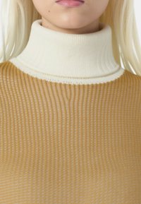 Maglione a collo alto con un design testurizzato e a coste. Il corpo è di un beige caldo, con un colletto bianco a contrasto. Materiale in maglia morbido.