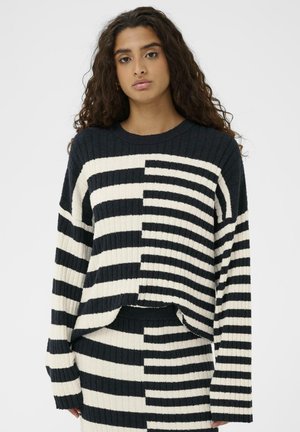 Gestrickter Pullover mit einer gerippten Textur, der ein gestreiftes Muster in Schwarz und Creme aufweist, mit entspanntem Schnitt und überschnittenen Schultern.