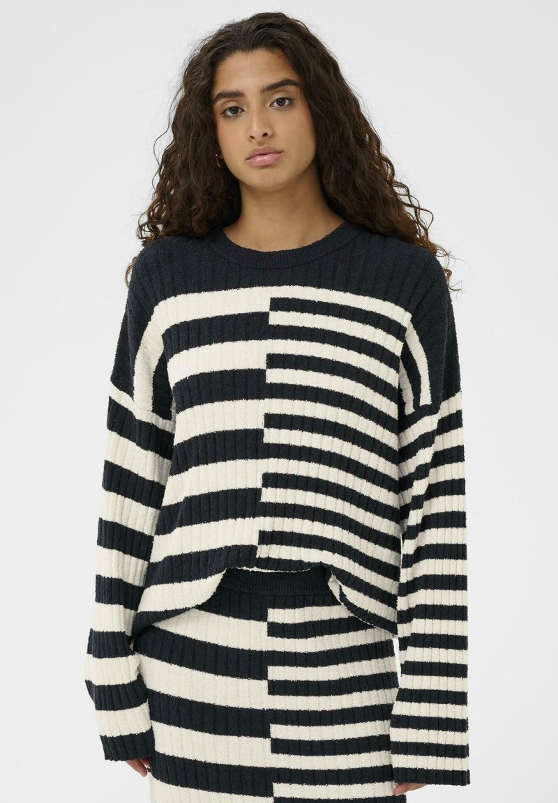 Gestrickter Pullover mit einer gerippten Textur, der ein gestreiftes Muster in Schwarz und Creme aufweist, mit entspanntem Schnitt und überschnittenen Schultern.