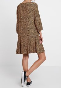 Vestido de estampado de leopardo con mangas tres cuartos, falda acampanada y escote redondo. Hecho de una tela ligera con una textura suave.