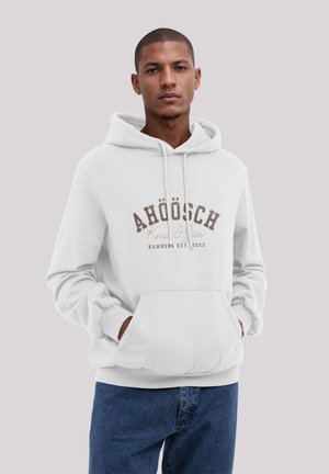 White hoodie with drawstring, front pocket, and printed logo in brown and beige. Features ribbed cuffs and waistband, paired with blue jeans.