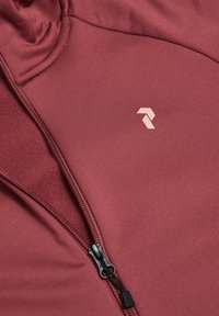 Ocvrt flis iz tkanine bordo barve s gladko teksturo, z dekorativnim črnim zadrgo in majhnim svetlim logotipom. Dizajn vključuje visok ovratnik in detajle šivov.