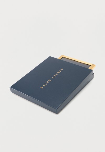 Κουτί Ralph Lauren σε ναυτικό μπλε χρώμα, λίγο ανοιχτό, που αποκαλύπτει καλλυντικό με καθρέφτη με χρυσή περίμετρο, σε λευκό φόντο.