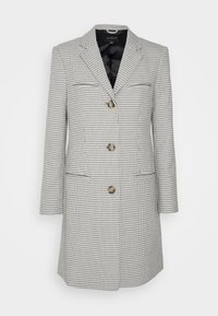 Rutigt kavaj i svart och vitt tyg, med notch-krage, tre bruna knappar och två framfickor. Slät svart foder innanför.