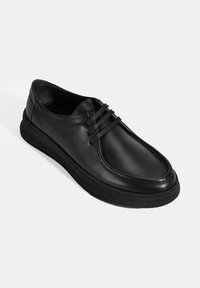 Schwarze Leder-Schnürschuhe mit runder Spitze und glatter Oberfläche, ausgestattet mit einer dicken schwarzen Gummisohle und minimalen Nähten.