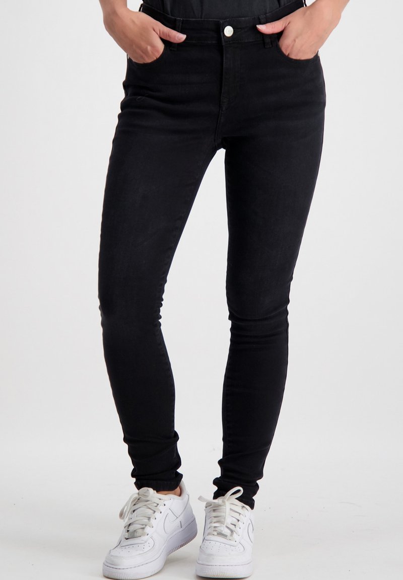 Zwarte skinny jeans, gemaakt van denim, met een hoge tailleband en vijf zakken. Het model draagt witte sneakers. Soepele textuur en geen zichtbare patronen.