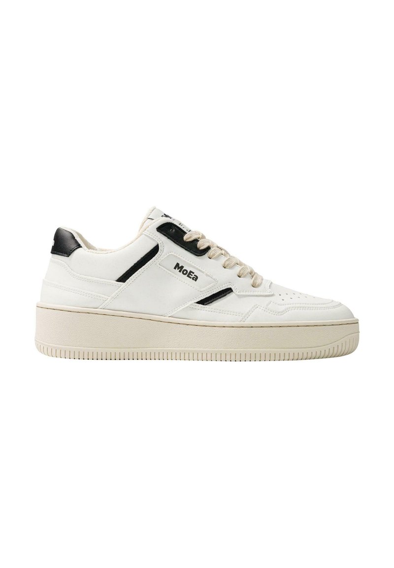 White sneaker with black accents, made from smooth leather. Features a thick sole, round toe, lace-up front, and perforated detailing.
