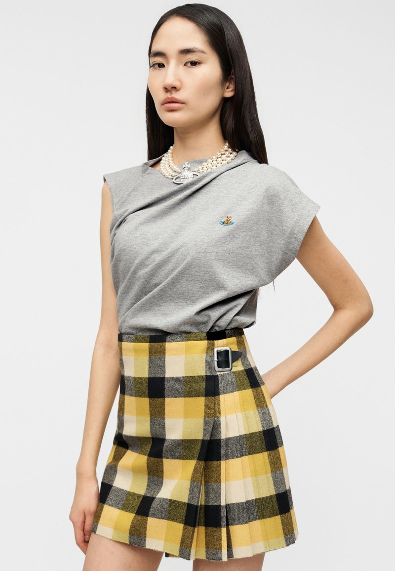 Gray short-sleeve shirt with a small embroidered design paired with a yellow and black plaid skirt featuring a buckle and pleats.