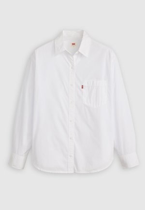 Camisa de botones de manga larga blanca, hecha de algodón. Presenta un cuello, un bolsillo frontal, dobladillo redondeado y una pequeña etiqueta de logo roja cerca del bolsillo.