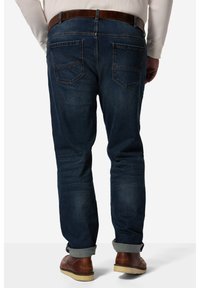 Jeans in denim blu scuro con vestibilità dritta, caratterizzati da due tasche posteriori e orli arrotolati. Una cintura in pelle marrone completa il design.