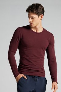 Burgunderfarbene Langarmshirt mit rundem Hals, figurbetontem Design, glatter Textur und gerippten Bündchen, kombiniert mit navyfarbenen Jogginghosen mit Kordelzug.