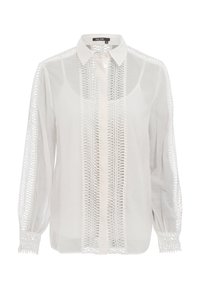 Weiße Bluse mit langen Ärmeln und Kragen, die filigrane Durchbrüche entlang der Vorderseite und Ärmel aufweist, aus leichtem Stoff gefertigt.