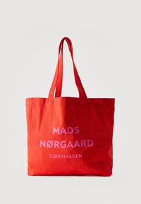 Κόκκινη υφασμάτινη τσάντα ώμου με διπλές λαβές και ροζ κείμενο "MADS NØRGAARD COPENHAGEN" στο μπροστινό μέρος, σε άσπρο φόντο.
