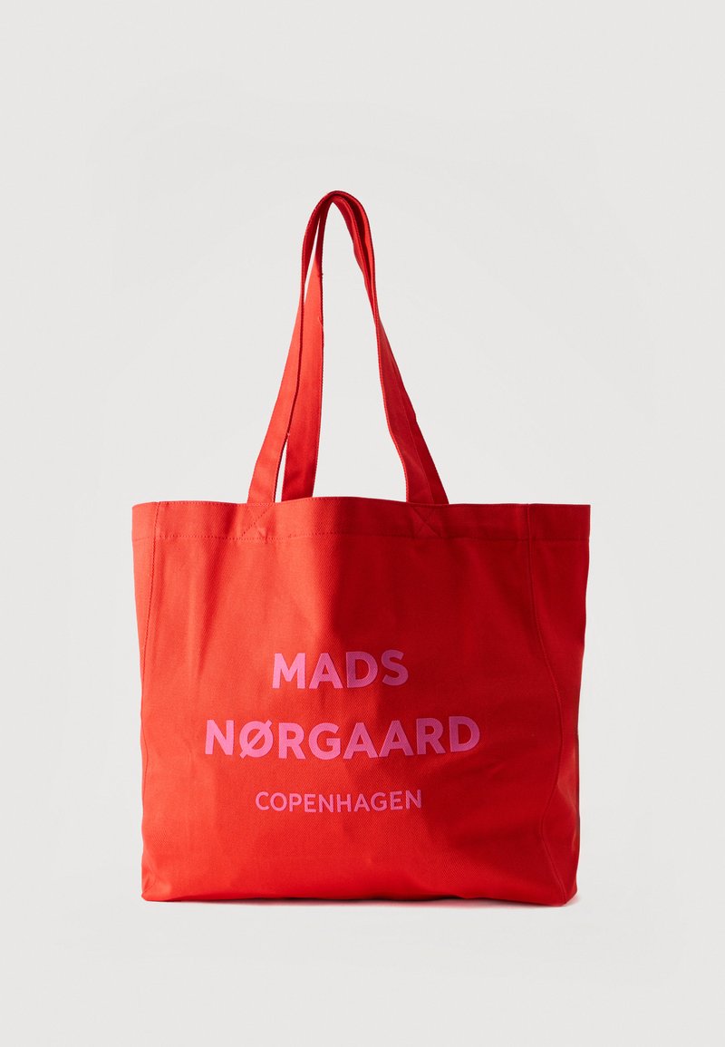 Κόκκινη υφασμάτινη τσάντα ώμου με διπλές λαβές και ροζ κείμενο "MADS NØRGAARD COPENHAGEN" στο μπροστινό μέρος, σε άσπρο φόντο.