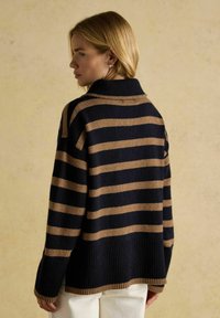 Gestreifter Pullover in Marineblau und Beige, mit hohem Kragen, gerippten Bündchen und Saum. Hergestellt aus weichem Stoff mit einer lockeren Passform.