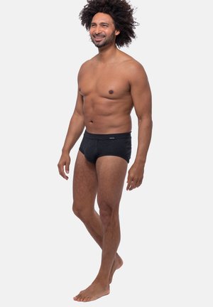 Schwarz gestreifte Unterhose mit einem weichen Gummibund, aus dehnbarem Stoff gefertigt. Das Design zeichnet sich durch eine figurbetonte Form und minimalen Markenaufdruck auf der Vorderseite aus.