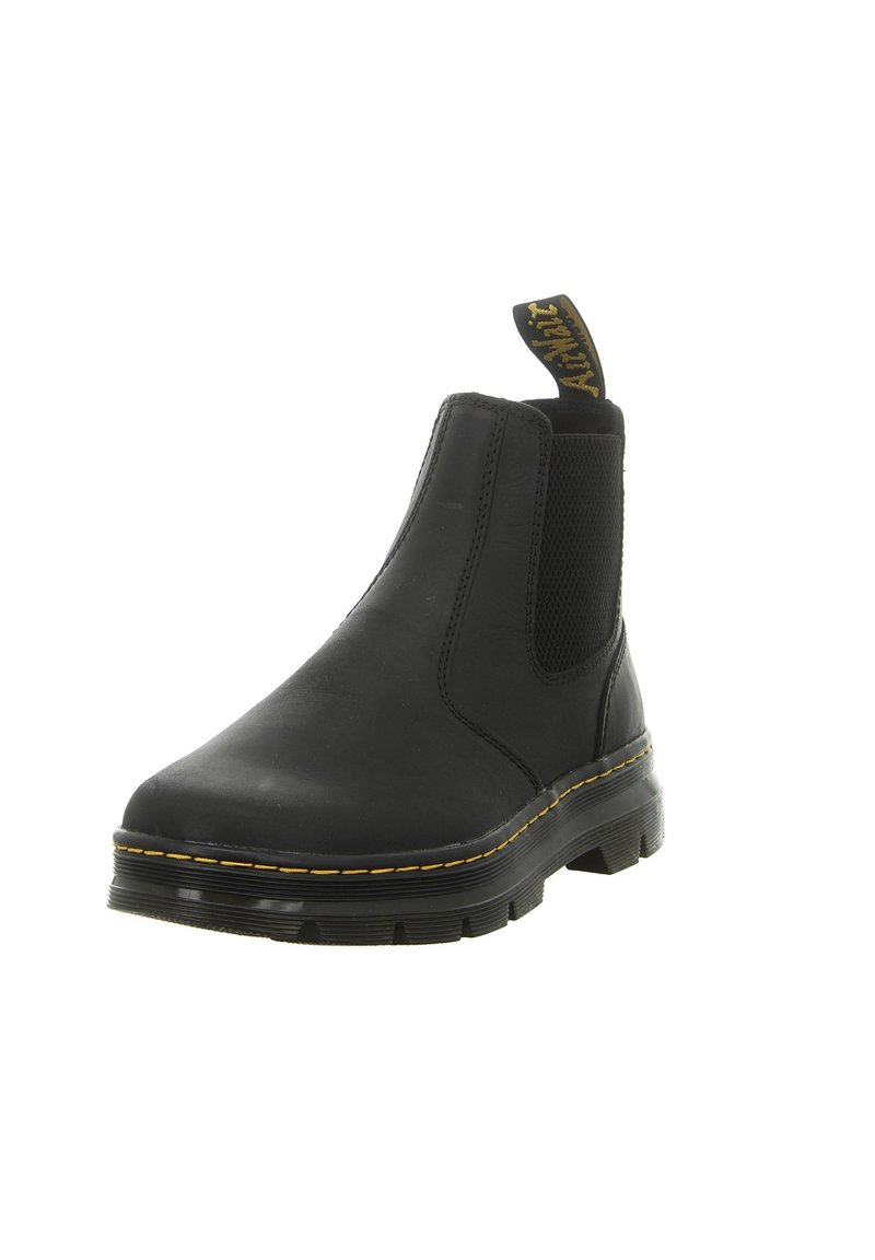 Black Chelsea boots with elastic side panels, textured rubber sole, and yellow stitching accents. Features a pull tab for easy wear.