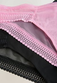 Tre par av lace-trimmed underkläder: rosa mesh ovan med vågig kant, svart mesh under med intrikata spetsdetaljer.
