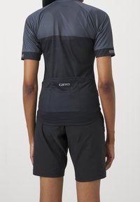 Svart cykeltröja med meshpaneler, korta ärmar och bakfickor. Kombinerad med svarta shorts, tillverkade av lätt material.