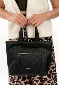 Mustast kohmakast nahast käekott kahe käepidemega, ees lukuga tasku ja madalal esiküljel peen logo. Jäik kuju ja tekstureeritud pind.