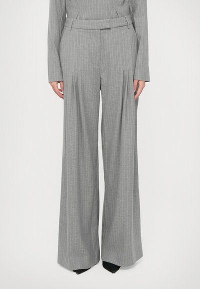 Pantalones de tiro ancho de rayas grises con cinturón en la cintura, que presentan un corte estructurado y una tela fluida. Los pliegues visibles realzan el diseño.