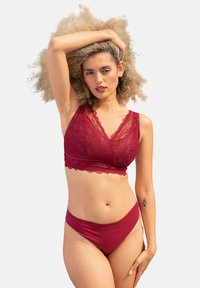 Burgunderfarbene Spitzenbralette mit gewellten Kanten, kombiniert mit passendem nahtlosem Bikini-Unterwäsche-Stil. Glatte Textur und elastischer Stoff.