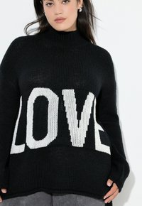 Czarny sweter dzianinowy z wysokim kołnierzem, zdobiony dużymi białymi literami "LOVE". Luźny krój z prążkowanymi mankietami i dołem, o fakturowanej tkaninie.