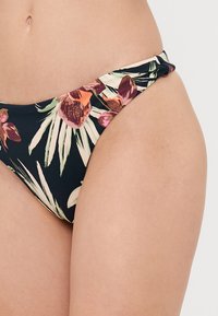 Sötét szövetből készült bikini alsó, színes virágmintával, levél- és orchideaábrázolásokkal. A dizájn kihúzott oldal részlettel rendelkezik.