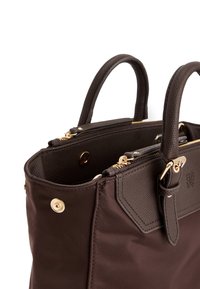 Bruine nylon handtas met getextureerde leren accenten, gouden hardware, dubbele handvatten en ritssluiting. Interieur toont details van het compartiment.