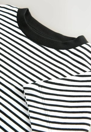 Close-up van een gestreept zwart-wit shirt, met een zwarte kraag en een zichtbare zak, waarbij de stoffen- en stikdetails worden benadrukt.