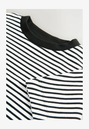 Gros plan sur une chemise à rayures noir et blanche, avec un col noir et une poche visible, mettant en valeur le tissu et les détails de couture.