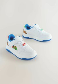 Weiße Turnschuhe mit blauen Sohlen, die ein "Super Mario"-Logo, einen verstellbaren Riemen und farbenfrohe Akzente in Rot und Grün aufweisen. Strukturierte Details an den Seiten.