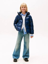 Marineblå dunjakke med hette, glidelåsfremme og sidelommer, kombinert med lyseblå rutet skjorte, vide jeans og svarte sko.