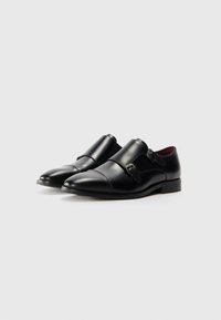 Schwarze Lederschuhe mit einem eleganten Design, spitzem Zeh und doppelten Schnallen. Glatte Textur mit einem subtilen Glanz und kontrastierender Innenfarbe.