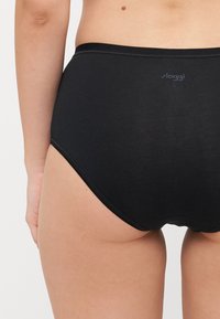 Black high-waisted brief made of soft fabric, featuring a smooth texture, elastic waistband, and minimalistic logo detail.