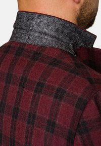 Bordowy plaidowany żakiet z szarym filcowym kołnierzem. Posiada wzór w kratę i teksturowany materiał, prezentując detale krawieckie przy szyi.