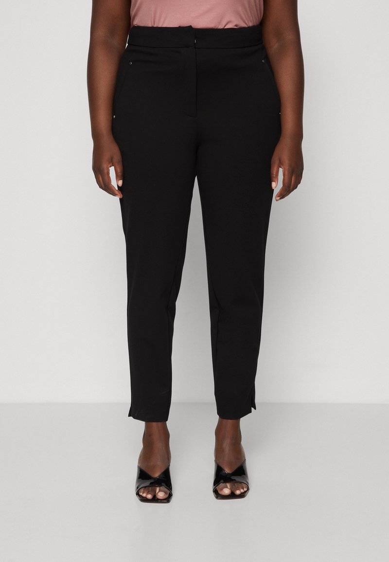 Pantalons noirs ajustés avec une coupe slim, présentant une taille haute et des fentes sur les côtés, fabriqués dans un tissu lisse et extensible.