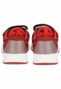 Scarpe da ginnastica rosse con tomaia in rete, dotate di una cinghia in velcro, suola bianca e accenti in rosso scuro a contrasto. La vista posteriore mostra un motivo testurizzato.