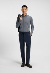 Marineblauwe broek met een elastische tailleband, gecombineerd met een langemouw overhemd met een geometrisch patroon in grijstinten.
