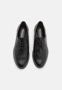 Sorte skinn lisseskos med brogue-design, med subtil søm og glatt overflate. Størrelse 37 trykt inni.