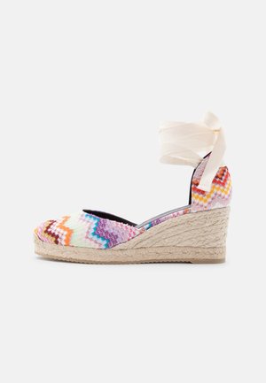 Πλατφόρμα εσπαντρίγια με πολύχρωμο ύφασμα άνω μέρους σε ζιγκ-ζαγκ σχέδιο, τακούνι τυλιγμένο με σχοινί τζούτης και λευκό κορδόνι που δένει στον αστράγαλο σε λευκό φόντο.