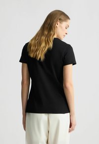 Zwarte t-shirt met korte mouwen, gemaakt van katoen en met een standaard pasvorm. Voorzien van een ronde hals en een zachte structuur. Eenvoudig ontwerp zonder patronen.