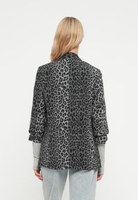 Blazer s leopardím vzorem v šedých tónech, s strukturovanými rameny, tříčtvrtinovými rukávy a hladkým texturovaným materiálem.