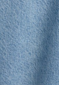 Tejido de denim azul claro con un patrón de tejido diagonal, que muestra una superficie ligeramente texturizada y sutiles variaciones de color.