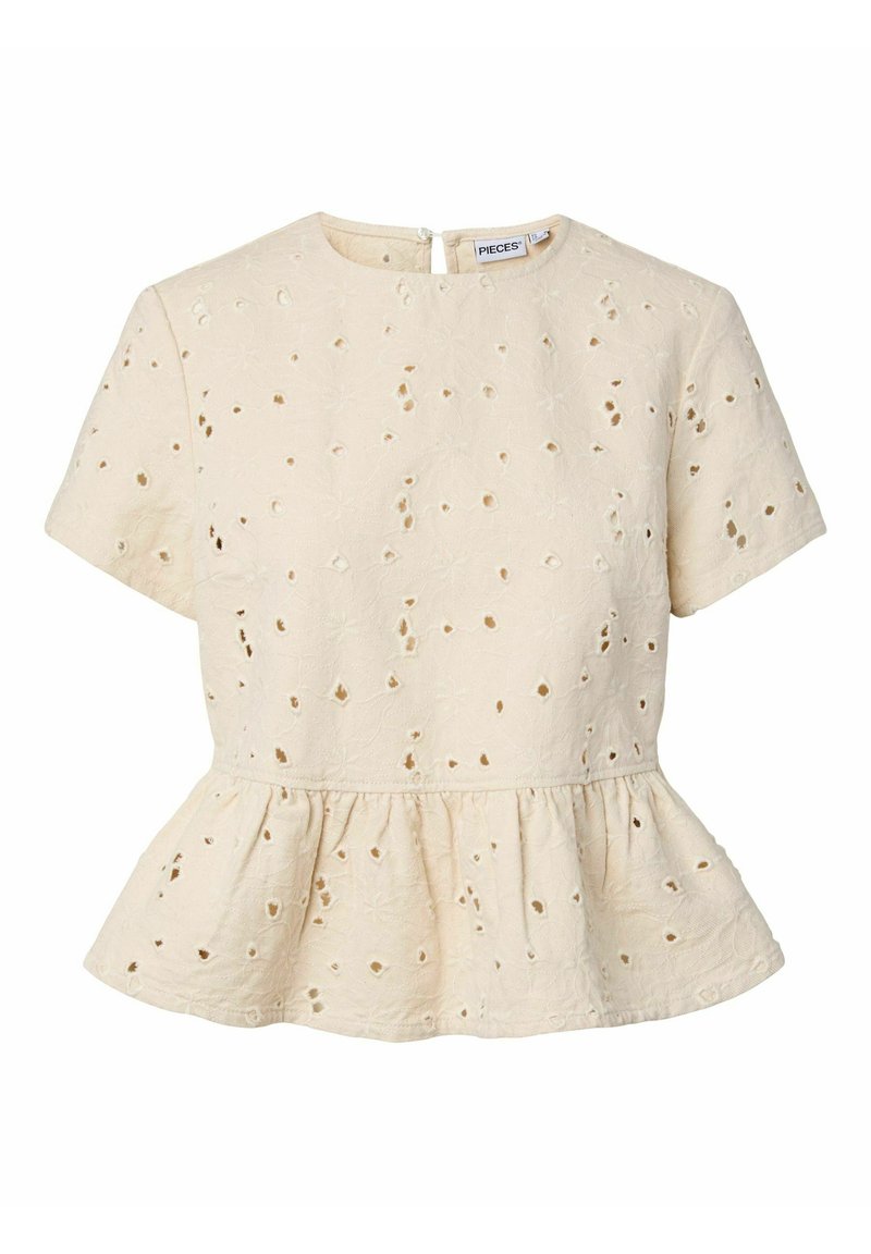 Blouse beige à manches courtes avec col rond, broderie florale ajourée et détail basque à la taille.